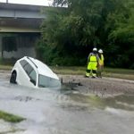 Woman rescued after car plunges into flooded sinkhole