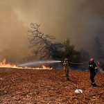 Helicopters and firefighters fight fast-moving wildfire near Athens